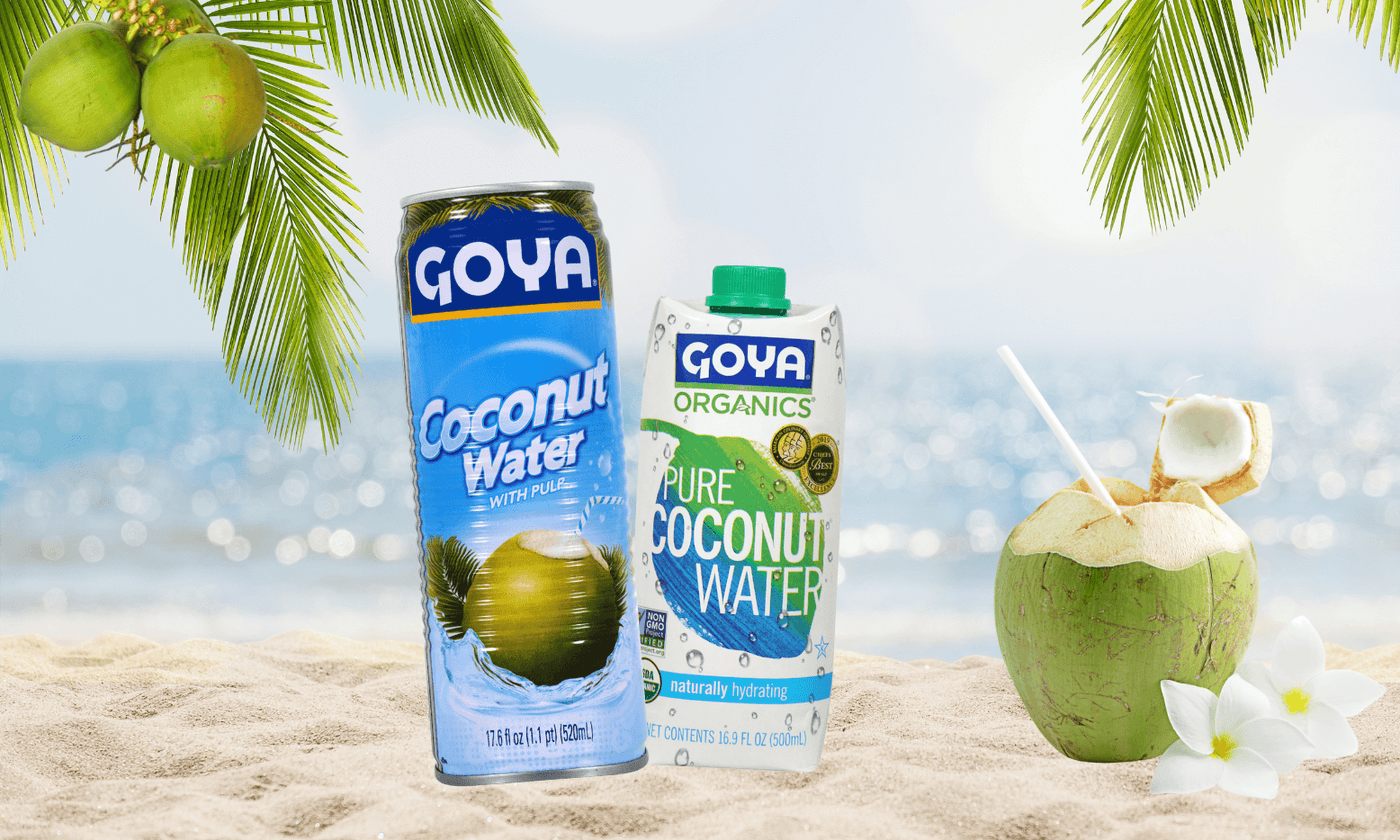 various Goya coconut water next to coconut on the beach
