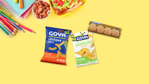 Various Goya products in yellow background with pencils, note books, almond and lunch.